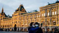Two women wearing protective face masks to protect from the novel coronavirus, COVID-19, use their smartphone to take a selfie while standing on Red Square in downtown Moscow on March 18, 2020. / AFP / Dimitar DILKOFF
