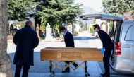 Undertakers wearing a face mask unload a coffin out of a hearse on March 16, 2020 at the Monumental cemetery of Bergamo, Lombardy, as burials of people who died of the new coronavirus are being conducted at the rythm of one every half hour. AFP / Piero Cr
