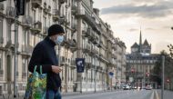 A man wearing a face mask uses a pedestrian crossing in front of Saint-Pierre Cathedral in Geneva on March 20, 2020, as the Swiss government further tightened measures against COVID-19, but said it would not follow other countries in ordering full confine