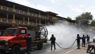 Firefighters from Ahmedabad Fire and Emergency Services spray disinfectant along a street during Gujarat's government-imposed lockdown as a preventive measure against the COVID-19 coronavirus, in Ahmedabad on March 24, 2020. / AFP / SAM PANTHAKY