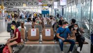 People wearing face masks sit on seats with signs telling travellers where they may sit, in order to observe social distancing rules amid concerns over the spread of the COVID-19 coronavirus, at Suvarnabhumi Airport in Bangkok on March 25, 2020. / AFP / J