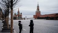 Police officers wearing face masks patrol on the empty Red square, with the St. Basil's Cathedral (L) and Kremlin's Spasskaya Tower (R) in the background, in Moscow on March 30, 2020. AFP / Dimitar DILKOFF
