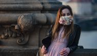 :A woman wearing a face mask stands on the Charles Bridge on March 28, 2020, in Prague, where most activities slowed down or came to a halt due to the spread of the novel coronavirus COVID-19. / AFP / Michal Cizek
