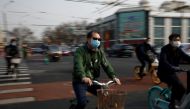 People wearing face masks ride bicycles on a street following an outbreak of the coronavirus disease (COVID-19), in Beijing, China March 30, 2020. REUTERS/Carlos Garcia Rawlins