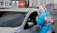 FILE PHOTO: A medical staff member in protective gear prepares to take samples from a visitor at a 'drive-thru' testing center for the novel coronavirus disease of COVID-19 in Yeungnam University Medical Center in Daegu, South Korea, March 3, 2020. REUTER