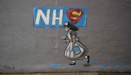 Graffiti depicting the badge of the fictional super heros Superman and Superwoman, and the logo of Britain's National Health Service (NHS) above street art of a nurse, are pictured on a wall in Pontefract, northern England on April 3, 2020, as life in Bri