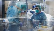 Healthcare workers wearing protective suits get ready to attend to a COVID-19 coronavirus patient at the Intensive Unit Care (ICU) of the Vall d'Hebron Hospital in Barcelona on April 6, 2020. Spain declared a fourth consecutive drop in the number of coron