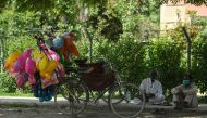 A balloon vendor (R) wearing a facemask waits for customers alongside a street during a government-imposed nationwide lockdown as a preventive measure against the spread of the COVID-19 coronavirus, in Islamabad on April 9, 2020./ AFP / Aamir QURESHI