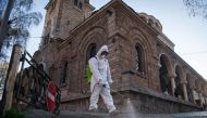 :TOPSHOT - A members of the Sofia's Municipality disinfects the area around the St. Nedelya Church in Sofia, to prevent the spread of the COVID-19, the novel coronavirus on April 11, 2020. . / AFP / NIKOLAY DOYCHINOV