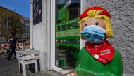 A lifesize promotional figure outside a bookstore has been fitted with a face cover in Berlin on April 16, 2020, amid a new coronavirus COVID-19 pandemic. / AFP / John MACDOUGALL

