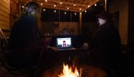 Neighbors sit around a fire-pit to watch Beyonce perform during the 