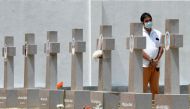A relative pays his respect at a graveyard for St. Sebastian's Church bomb blasts victims in Negombo on April 21, 2020, to mark the first anniversary of the attacks. AFP / LAKRUWAN WANNIARACHCHI
