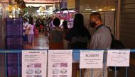 Instruction notice placards hang on a barrier as a man wearing a facemask as a prevention measure against the spread of the COVID-19 coronavirus queues to enter a wet market in Singapore on April 22, 2020. / AFP / ROSLAN RAHMAN