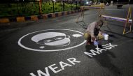 A man draws an awareness message on a road about wearing mask amid concerns about the spreading of coronavirus disease (COVID-19) in Ahmedabad, India, April 21, 2020. REUTERS/Amit Dave