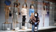 A woman wearing PPE (personal protective equipment), of a face mask as a precautionary measure against COVID-19, stands outside a Primark clothing store, closed-down due to COVID-19, on Oxford Street in central London on April 27, 2020.  AFP / Tolga AKMEN