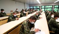 Swiss soldiers wearing protective face masks sit in a classroom as they install the contact tracking application created by the Swiss Federal Institute of Technology Lausanne (EPFL), using Bluetooth and a design called Decentralised Privacy-Preserving Pro