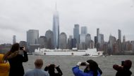 Spectators on the New Jersey shoreline take pictures as the U.S. Navy hospital ship USNS Comfort departs Manhattan and passes lower Manhattan and the World Trade Center building under heavy fog as it leaves to return to its home port of Norfolk, Virginia,