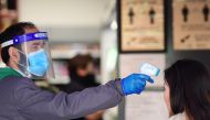 An employee takes the temperature of a customer at the entrance of a super market in China Town in London, following the outbreak of the coronavirus disease (COVID-19), London, Britain, May 2, 2020. Reuters/Toby Melville