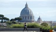 A woman walks with St. Peter's Basilica in the background, ahead of Pope Francis' Regina Coeli prayer which is to be held at the Vatican without public participation due to the coronavirus disease (COVID-19) outbreak, in Rome, Italy, May 3, 2020. REUTERS/