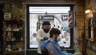 :Hairdresser David Cores cuts his first client's hair after reopening his barber shop in Pontevedra, on May 4, 2020, for the first time since the beginning of a national lockdown to prevent the spread of the COVID-19 disease./ AFP / MIGUEL RIOPA