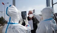 TOPSHOT - This photo taken on May 1, 2020 shows staff wearing hazmat suits as a precaution against the COVID-19 coronavirus checking the temperature of a driver at a customs checkpoint on the border with Russia at Suifenhe, in China's northeast Heilongjia