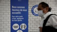 A wearing a protective face mask walks past a placard with health and social distancing informations at a metro station of Paris transport network (RATP) during the outbreak of the coronavirus disease (COVID-19) in Paris, France, May 5, 2020. REUTERS/Beno