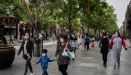 People wearing face masks as a preventive measure against the COVID-19 coronavirus walk on a street in Beijing on May 4, 2020. / AFP / NICOLAS ASFOURI