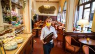 :Antje Roesler works the tables at the reopened Cafe Prag in Schwerin, northeastern Germany on May 9, 2020 amid the ongoing Covid-19, coronavirus pandemic. The traditional cafe and restaurant welcomed sit in customers after two months of closure as restau