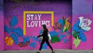 A woman wearing a protective face mask and gloves is seen walking past a mural, following the outbreak of the coronavirus disease (COVID-19), London, Britain, May 11, 2020. REUTERS/Dylan Martinez