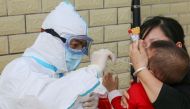 A medical staff member takes a swab sample from a child to test for the COVID-19 novel coronavirus in Jian in China's central Jiangxi province on May 13, 2020. China OUT / AFP / STR