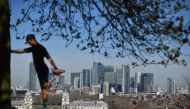(FILES) In this file photo taken on March 23, 2020 London's financial district Canary Wharf is seen as a man exercises in Greenwich Park in South London on March 23, 2020, as people come to terms with the governments request for social distancing as the C