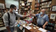 Bookseller Philippe Seyrat, wearing a protective face mask, talks with a customer at La Sorbonne bookstore in Nice as France softens its strict lockdown rules during the outbreak of the coronavirus disease (COVID-19) in France, May 13, 2020. REUTERS/Eric 