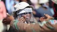 A woman wears a protective face shield during food distribution, as South Africa starts to relax some aspects of a stringent nationwide coronavirus disease (COVID-19) lockdown, in Diepsloot near Johannesburg, South Africa, May 8, 2020. REUTERS/Siphiwe Sib