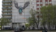 People wearing protective face masks cross a street near an apartment block, which is decorated with a mural dedicated to medical specialists involved in the fight against the coronavirus disease (COVID-19), in Odintsovo outside Moscow, Russia May 14, 202
