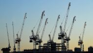 The sun sets beyond construction cranes standing over the building site for new apartments and a retail complex, at the Battersea Power Station redevelopment site in south London on May 14, 2020 following an easing of the novel coronavirus COVID-19 lockdo