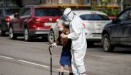 :A medical specialist, wearing a protective suit amid the coronavirus disease (COVID-19) outbreak, assists an elderly woman to cross a road in Moscow, Russia May 14, 2020. REUTERS/Shamil Zhumatov
