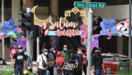 People wearing face masks amid concern over the spread of the COVID-19 coronavirus wait at a road crossing with building displays of festive decorations ahead of Eid al-Fitr which marks the end of the Muslim holy month of Ramadan, at the Geylang Serai mar