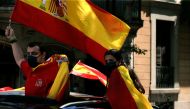 Demonstrators wave Spanish flags from their car during a 
