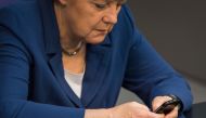(FILES) This file photo taken on July 3, 2015 shows German Chancellor Angela Merkel types on her mobile phone while attending a sitting of the Bundestag, Germany's lower house of parliament in Berlin. AFP / Odd ANDERSEN