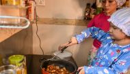 This photo taken on May 21, 2020 shows Moe Myint May Thu (R) and her mother Honey Cho cooking while filming a video at their house in Yangon. AFP / Ye Aung Thu 