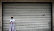 A woman wearing a face mask amid concerns over the spread of the COVID-19 coronavirus uses her phone as she stands in front of a closed department store in Tokyo on May 26, 2020. AFP / Behrouz MEHRI