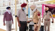 A police personnel (2R) checks a Sikh devotee (2L) as he arrives at the Golden Temple ahead of the 36th Operation Blue Star anniversary in Amritsar on June 5, 2020.  / AFP / NARINDER NANU
