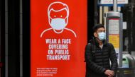 FILE PHOTO: A man wearing a mask waits at a bus stop in London, following the outbreak of the coronavirus disease (COVID-19), London, Britain, June 5, 2020. REUTERS/Toby Melville/File Photo
