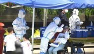 A health worker (2nd-L) wearing a protective suit takes a swab test on a woman in Beijing on June 16, 2020. AFP / Noel Celis
