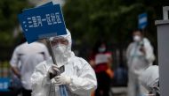 Medical staff in full protective gear carry signs to assist people who live near or who have visited the Xinfadi Market, a wholesale food market where a new COVID-19 coronavirus cluster has emerged, as they arrive for testing in Beijing on June 17, 2020. 