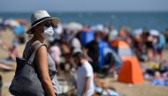 A woman wearing a face mask or covering as a precautionary measure against spreading COVID-19, arrives on the beach in the sea in Southend on Sea, south east England, on June 24, 2020. AFP / Ben STANSALL