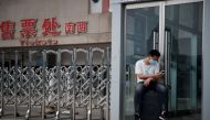 A man wears a protective mask as he sits on his suitcase at the Beijing West Railway Station, after an outbreak of the coronavirus disease (COVID-19), in Beijing, China July 3, 2020. REUTERS/Thomas Peter