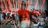 A woman wearing a face mask has her hair curled by a special equipment at a beauty salon in Bangkok on July 12, 2020. / AFP / Mladen ANTONOV