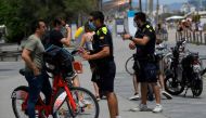 Catalan municipal police officers ask citizens to wear face masks at Barceloneta Beach in Barcelona on July 9, 2020. Regional officials in Catalonia said they want to toughen the existing rules to make wearing masks compulsory in public, to stem a rising 