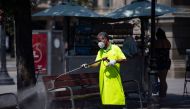A municipal worker cleans a bench at Catalonia square in Barcelona on July 18, 2020. Four million residents of Barcelona have been urged to stay at home as virus cases rise, while EU leaders were set to meet again in Brussels, seeking to rescue Europe's e